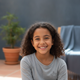 A happy young girl, 8-10 years old, smiling at the camera, conveying joy and satisfaction.